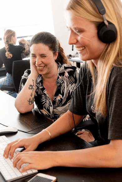 two women smiling at the computer